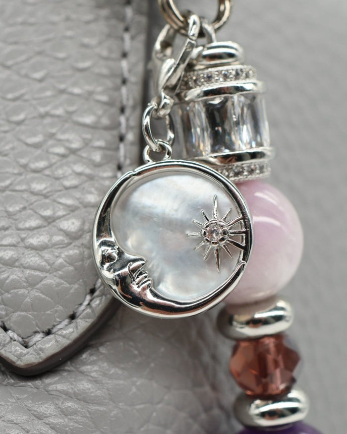 LD Keyfinder Amethyst Moon charm with moon and star, amethyst, kunzite, and glass beads on a grey textured background.