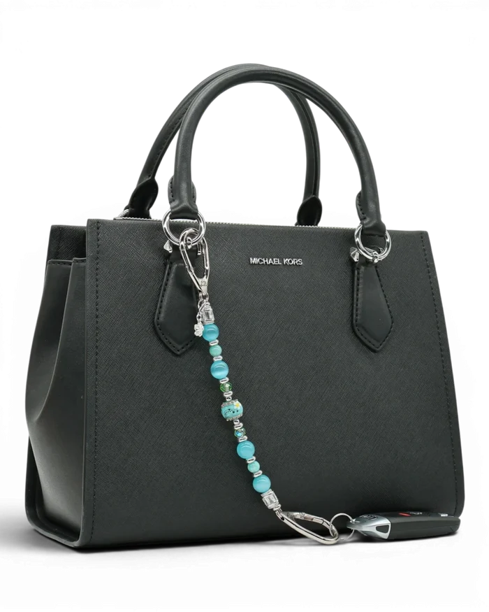 LD Keyfinder Azure Meadow beaded charm with aqua blue, green, and white daisy lampwork glass beads on a black handbag.