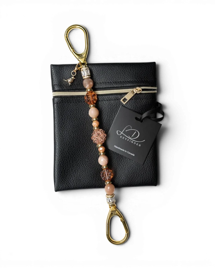 LD Keyfinder Birdsong Bliss beaded keychain with sunstone, peach glass, and gold-plated bird charm on a black pouch.