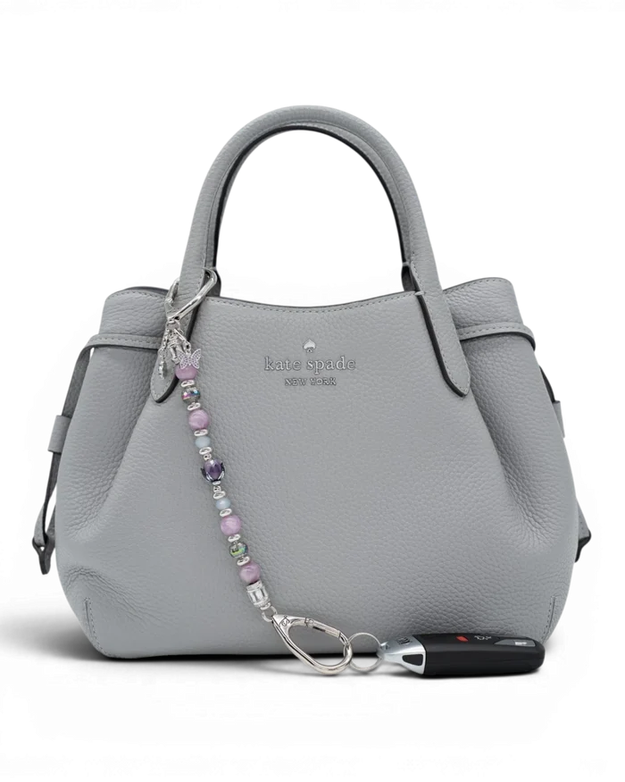 LD Keyfinder Blooming Joy beaded keychain with Lepidolite, Jade, and glass tulip charm attached to a grey leather handbag