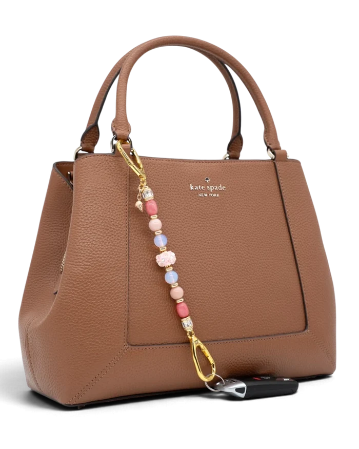 LD Keyfinder Blush Sorbetto beaded accessory with pink gemstones and gold ice cream charm attached to a brown handbag.