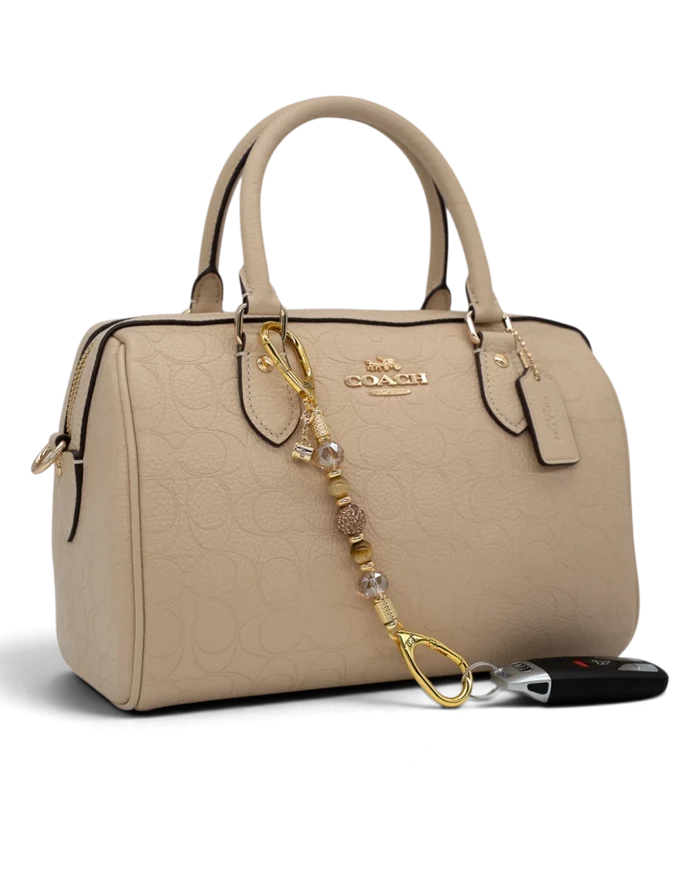 LD Keyfinder Caramel Latte-Mini beaded keychain with Tiger Eye gemstones and gold coffee charm on a beige handbag.