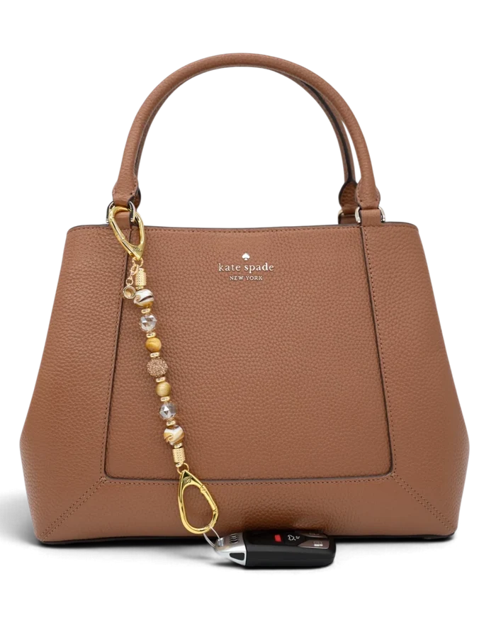 LD Keyfinder Caramel Latte beaded accessory attached to a brown leather handbag with a car key