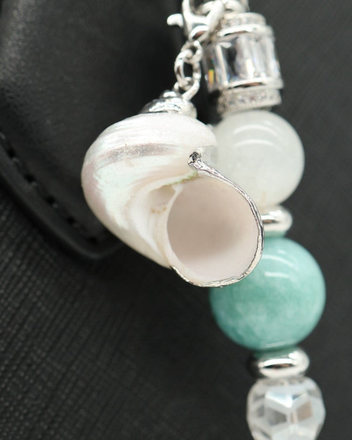 LD Keyfinder Caribbean Pearl accessory featuring a shell charm, moonstone, aqua jade, and glass beads on a black bag.