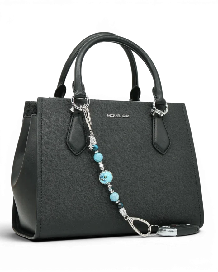 LD Keyfinder Celestial Tide keychain with turquoise, aqua, blue tiger eye, larimar beads, and silver star charm on black handbag.