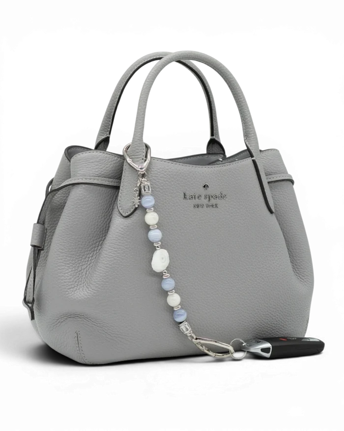 LD Keyfinder Cloud Dancer accessory with blue lace agate and moonstone beads attached to a grey leather handbag.
