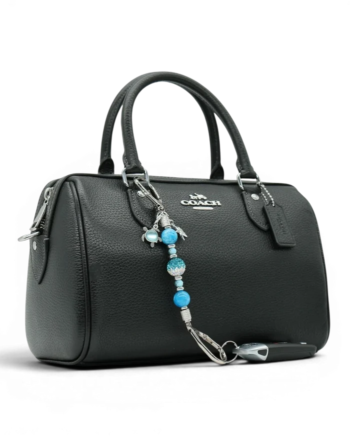 LD Keyfinder Coastal Tide Mini keychain with blue gemstone beads, turtle and starfish charms attached to a black handbag.