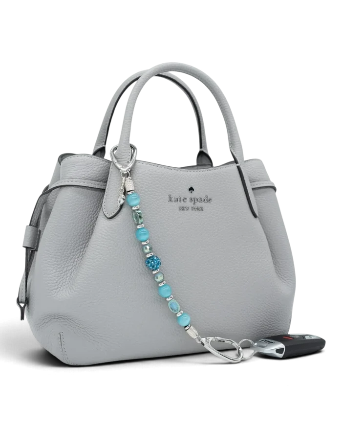 LD Keyfinder Dolphin Dream beaded key chain with aqua glass beads and a rhinestone dolphin charm on a grey handbag.