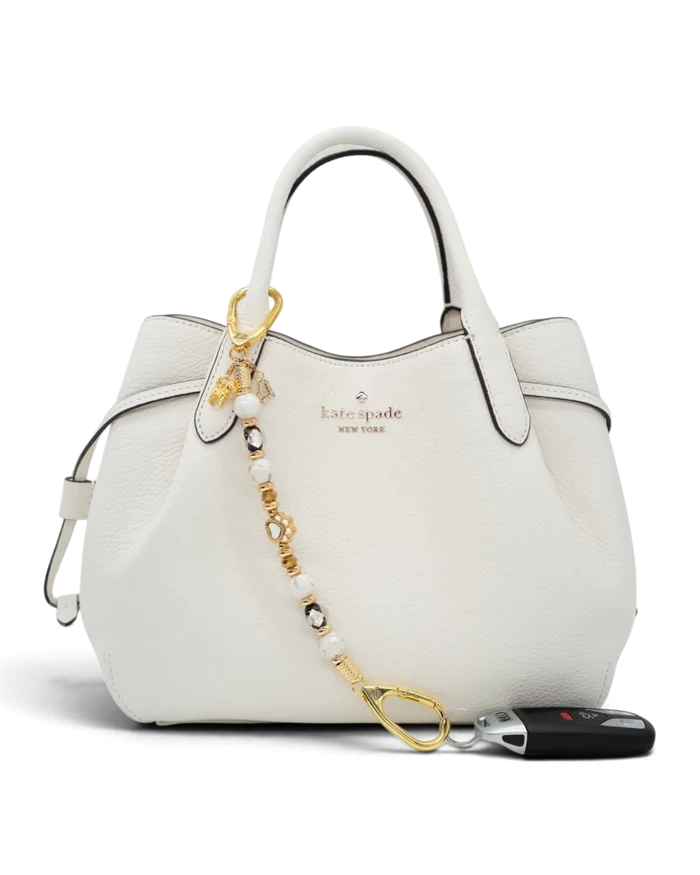 LD Keyfinder Furever Love beaded key chain with gold paw charm and white seashell beads attached to a white handbag.
