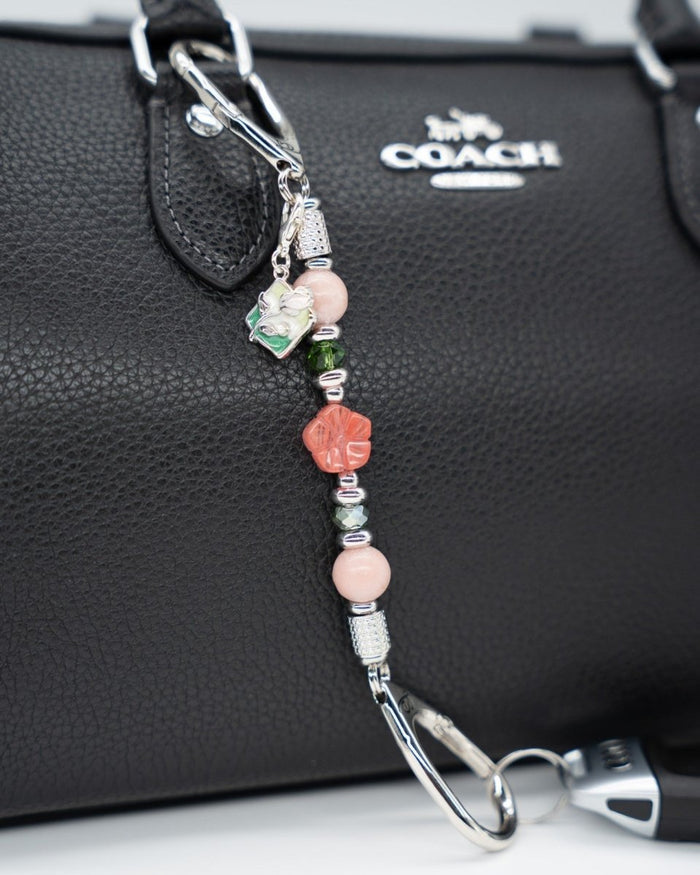 LD Keyfinder Garden Bliss Mini featuring pink opal, cherry quartz flower, and green glass beads on a black handbag.