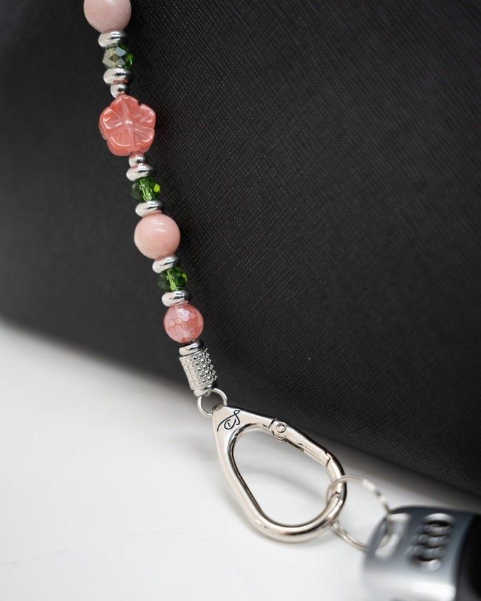 LD Keyfinder Garden Bliss beaded keychain with cherry quartz, pink opal, and green glass beads on a black bag.