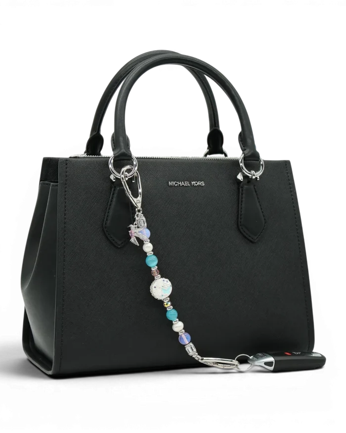 LD Keyfinder Garden Serenade beaded accessory with pearls, opalite, and hummingbird charm attached to a black handbag.