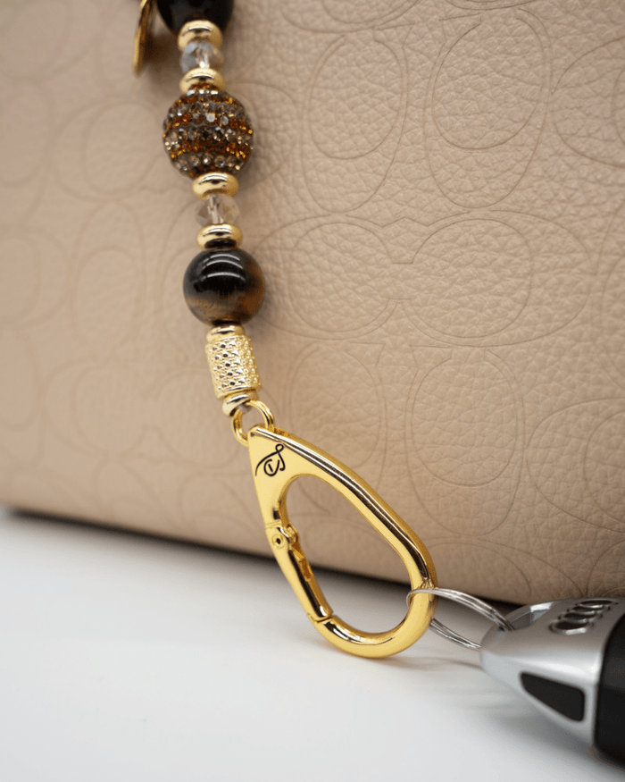 LD Keyfinder Golden Equinox-Mini featuring Tiger Eye beads, gold-plated accents, and a sun and moon charm on a bag