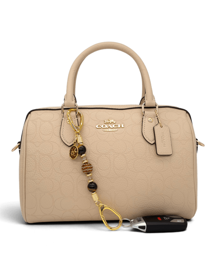LD Keyfinder Golden Equinox-Mini charm with Tiger Eye beads and sun and moon pendant attached to a beige Coach handbag
