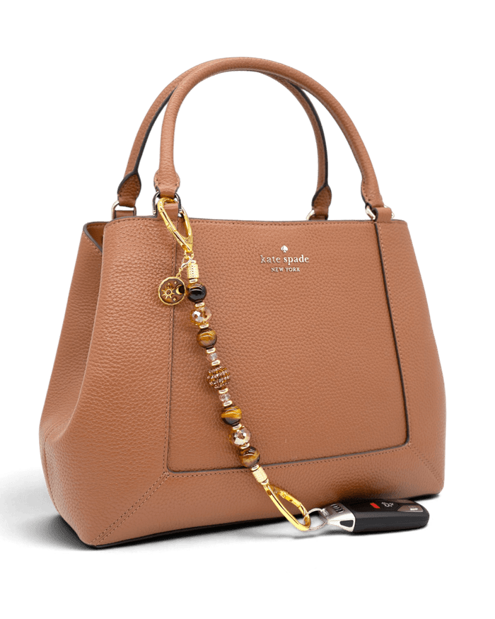 LD Keyfinder Golden Equinox beaded accessory with Tiger Eye, rhinestones, and sun and moon charm attached to a handbag