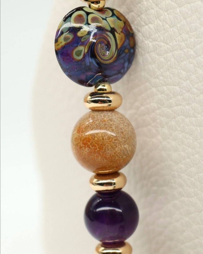 LD Keyfinder Golden Nebula necklace with artisan glass bead, fossil coral, amethyst, and gold-plated accents.