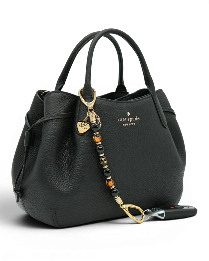 LD Keyfinder Golden Purrs beaded key chain with black obsidian and gold foil lampwork beads attached to a black handbag.