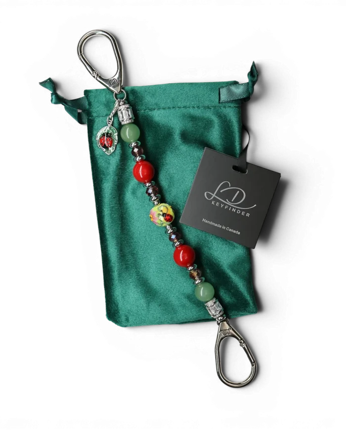 LD Keyfinder Ladybug Love beaded keychain with green aventurine, red shell pearls, and a ladybug charm on velvet bag