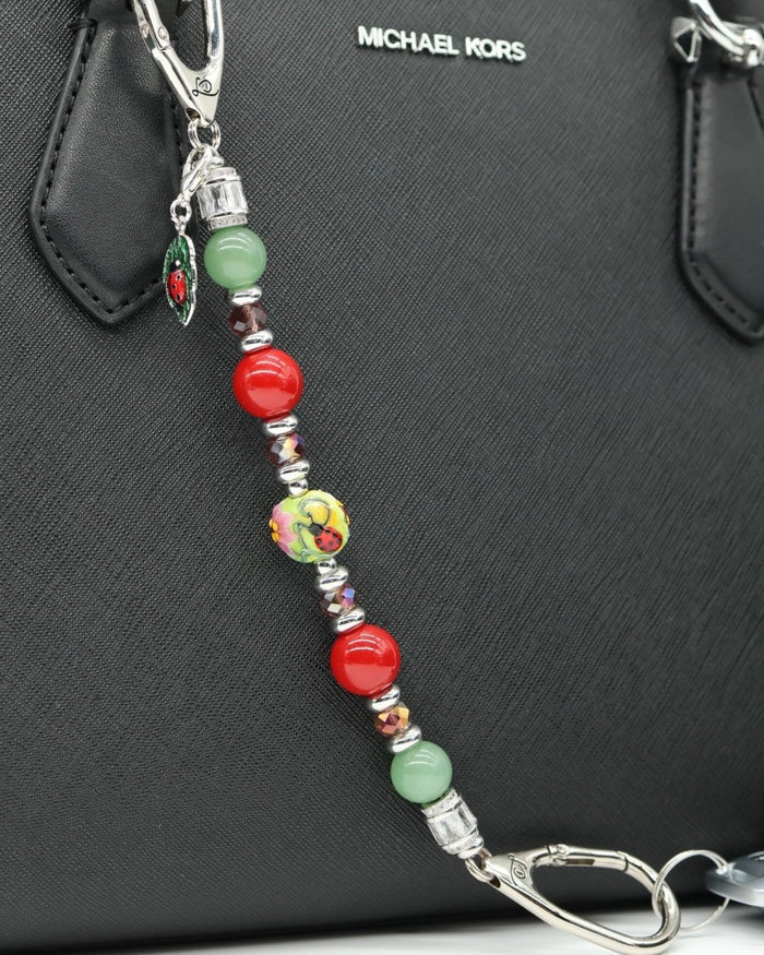 LD Keyfinder Ladybug Love accessory with green aventurine, red shell pearls, and artisan glass bead on a black bag.