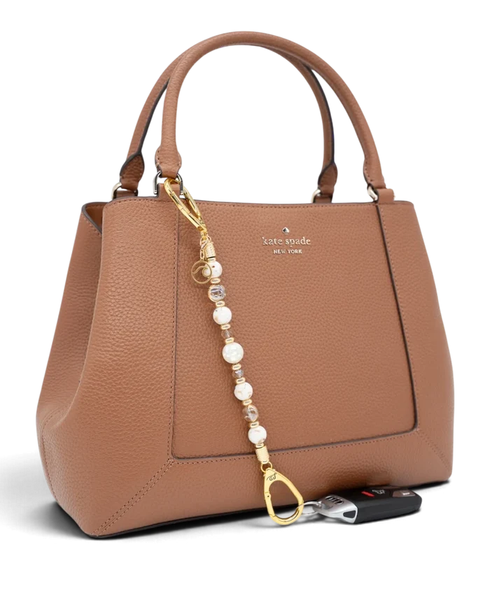 LD Keyfinder Mediterranean Glow beaded accessory with Mother of Pearl, ivory shells, and gold charms on a brown bag