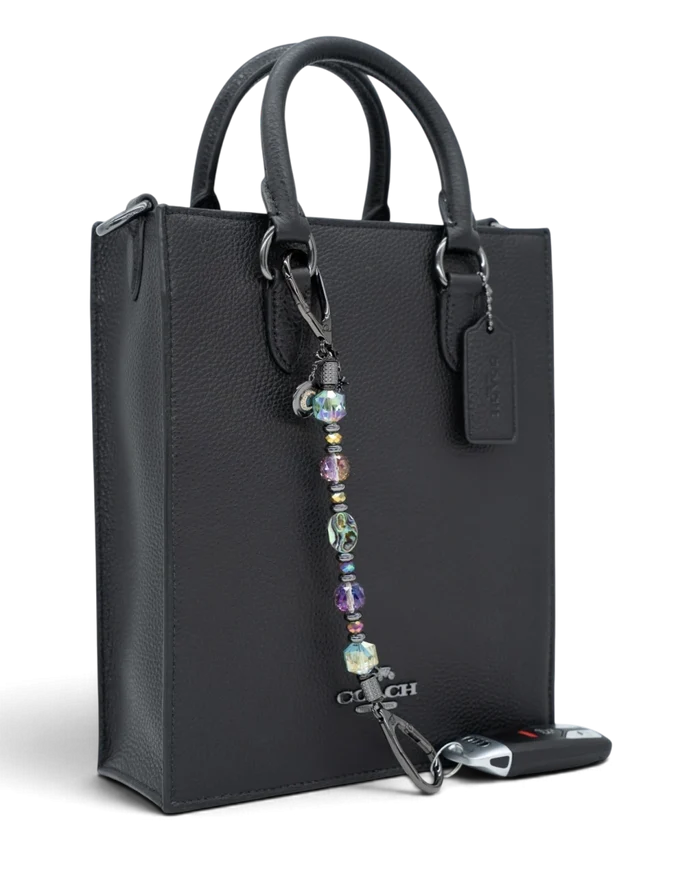 LD Keyfinder Midnight Aurora beaded keychain with abalone shell, rainbow crystals, and moon charm on a black handbag.