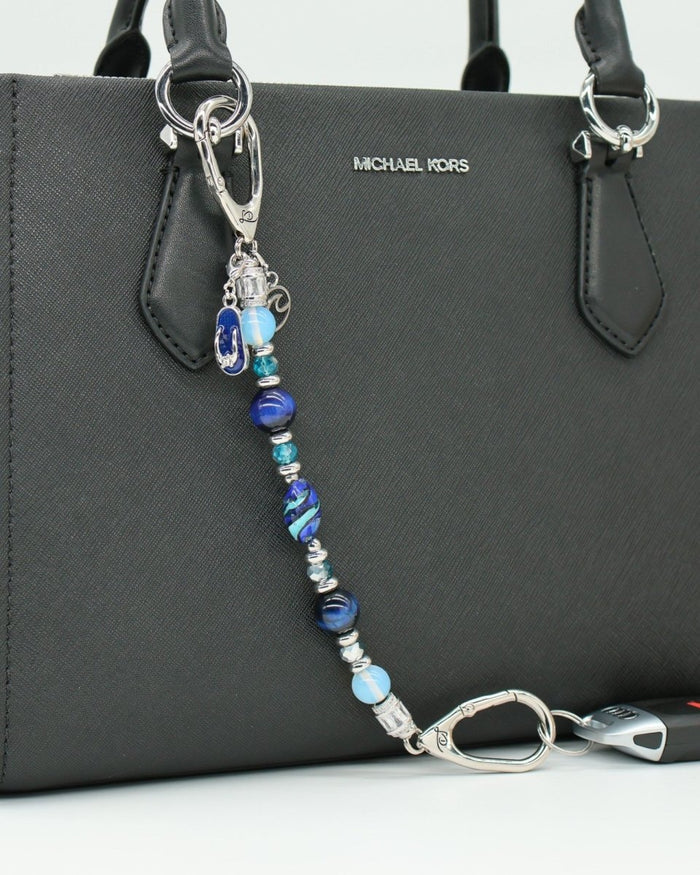 LD Keyfinder Ocean Mosaic beaded key chain with blue tiger eye, opalite, and artisan glass beads on a black handbag.
