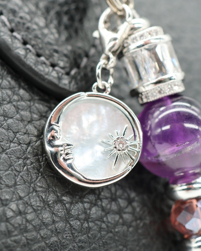 LD Keyfinder Petite Amethyst Moon keychain with moon and star charm, amethyst beads, and rhinestone accents on black textured background.