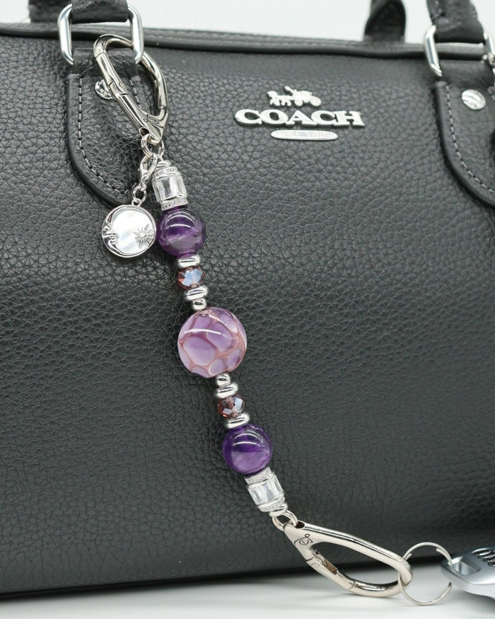 LD Keyfinder Petite Amethyst Moon charm with amethyst, glass beads, and moon charm on a black purse.