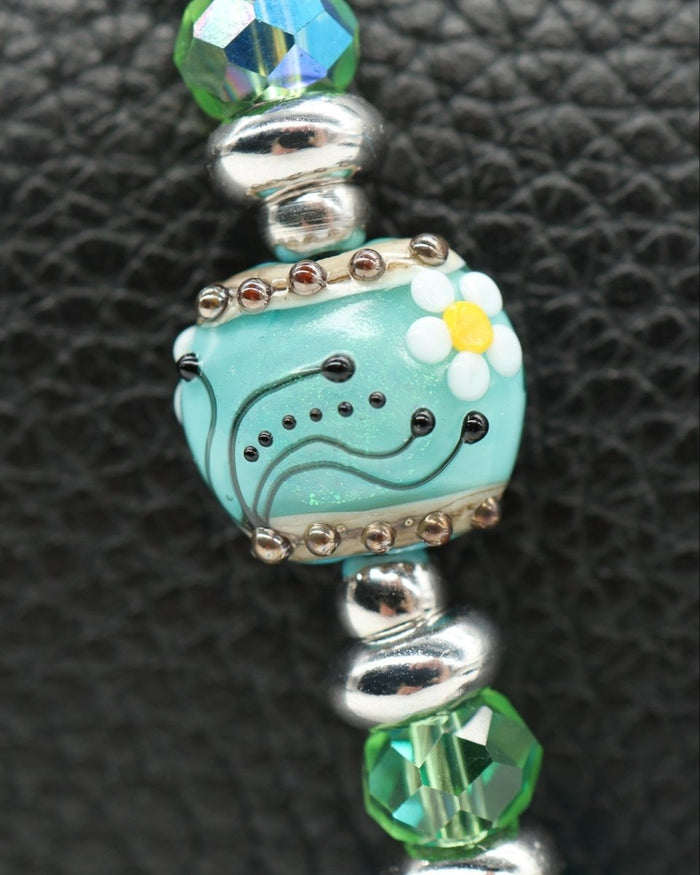 LD Keyfinder Petite Azure Meadow bracelet with aqua blue cat's eye beads, faceted green glass beads, and a lampwork glass daisy bead.