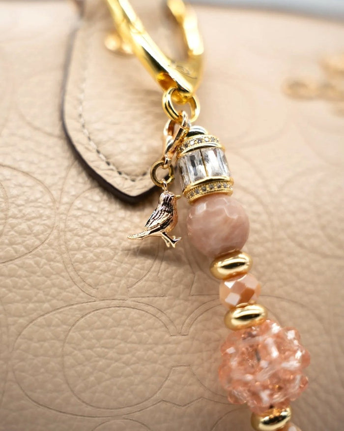 LD Keyfinder Petite Birdsong Bliss featuring a gold bird charm, sunstone beads, and peach glass on a gold clasp.