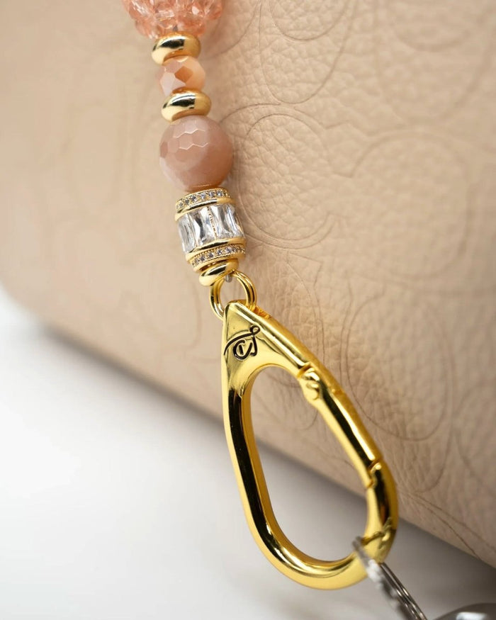 LD Keyfinder Petite Birdsong Bliss featuring peach glass, sunstone beads, and a gold-plated bird charm on a handbag.