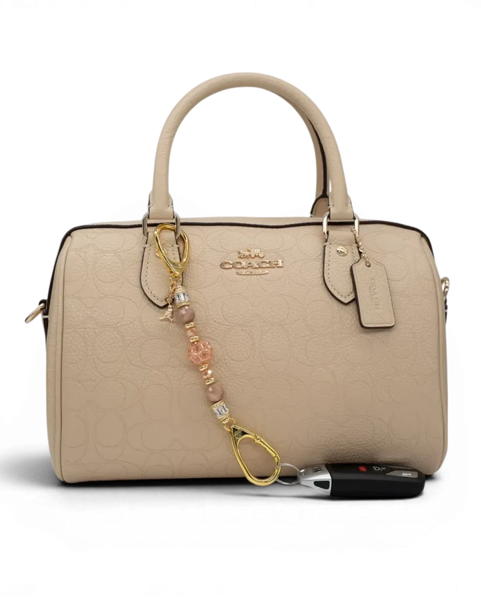 LD Keyfinder Petite Birdsong Bliss beaded accessory with sunstone and peach glass attached to a beige leather handbag.
