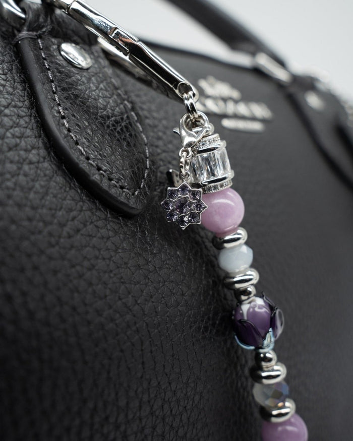 LD Keyfinder Petite Blooming Joy accessory with lavender Lepidolite, purple Jade, and glass tulip on a black handbag