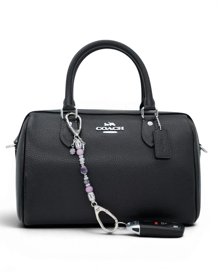 LD Keyfinder Petite Blooming Joy beaded accessory with lavender Lepidolite and purple Jade attached to a black handbag.