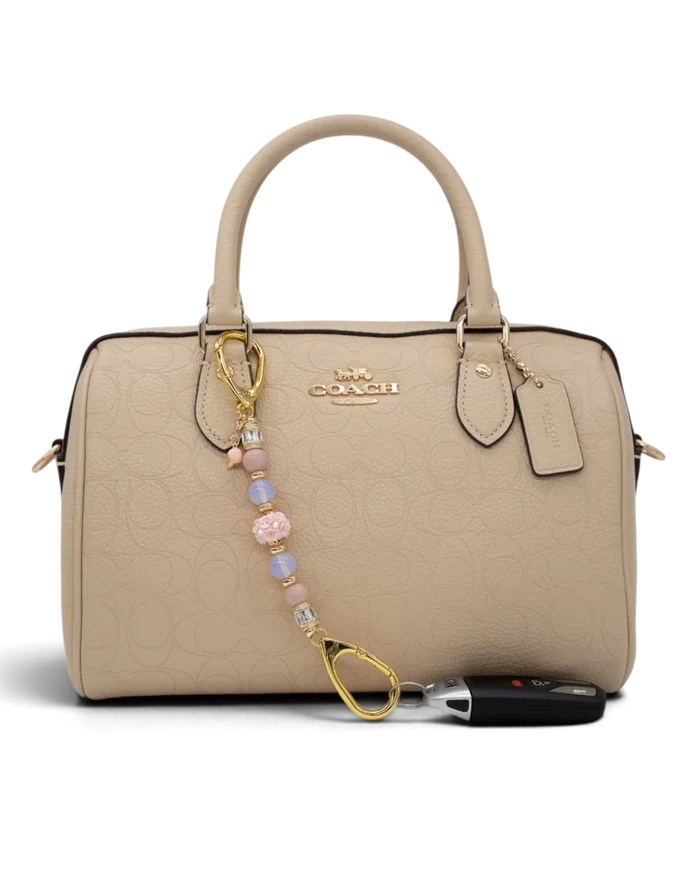 LD Keyfinder Petite Blush Sorbetto beaded accessory with pink opal, opalite, and gold ice cream charm on a beige bag