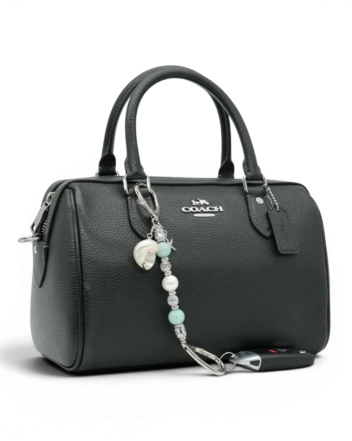LD Keyfinder Petite Caribbean Pearl beaded charm with shell and starfish accents attached to a black leather handbag.