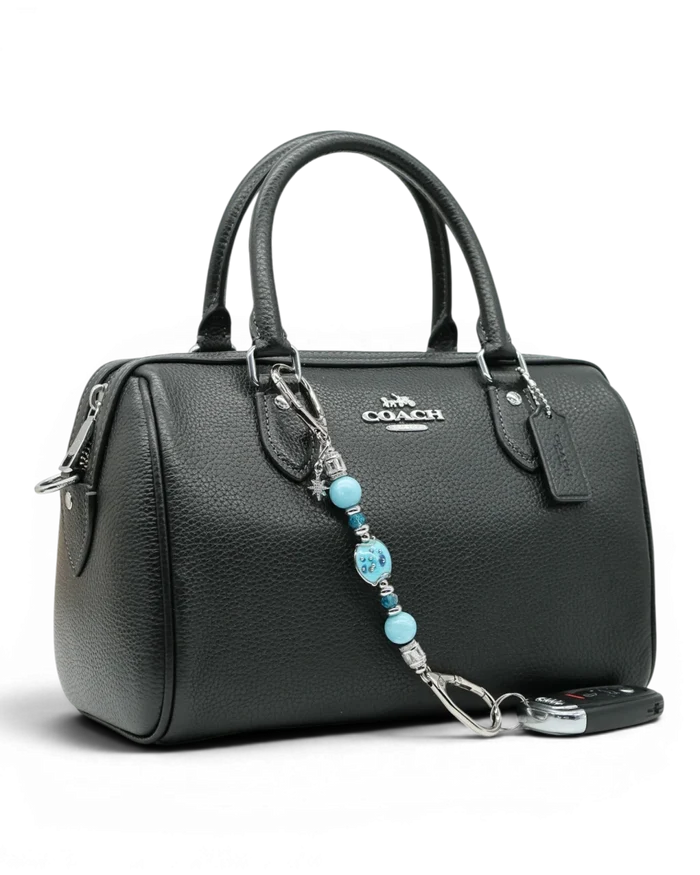 LD Keyfinder Petite Celestial Tide charm with turquoise, aqua, and silver beads, and a star charm, attached to a black handbag.