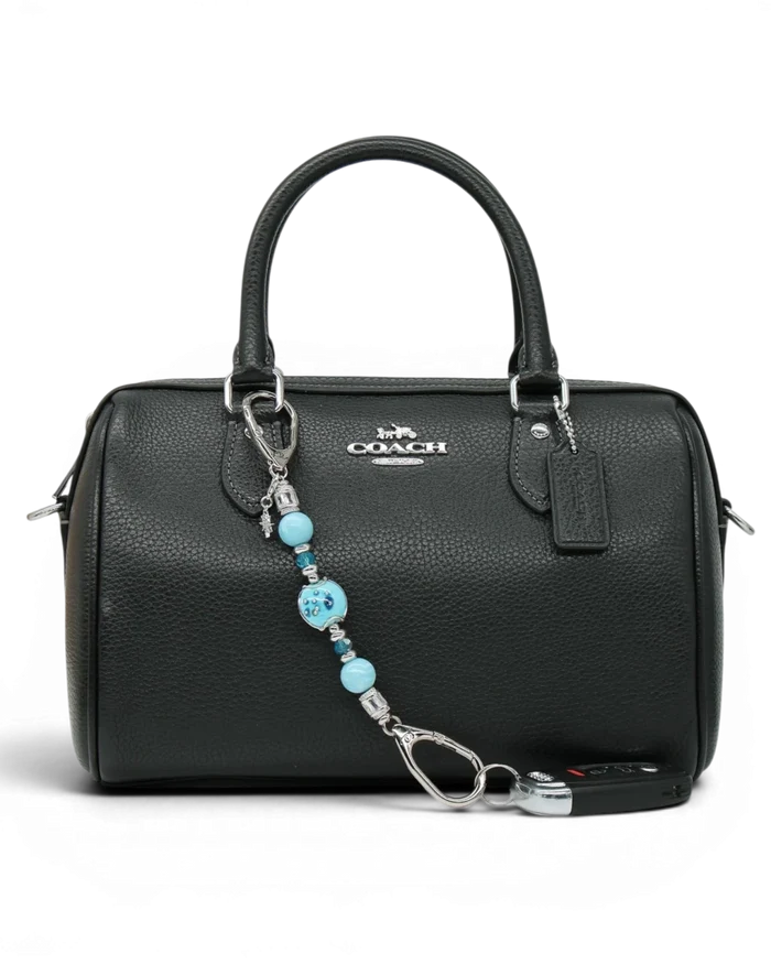 LD Keyfinder Petite Celestial Tide keychain with turquoise, aqua, and silver beads and a star charm attached to a black handbag.