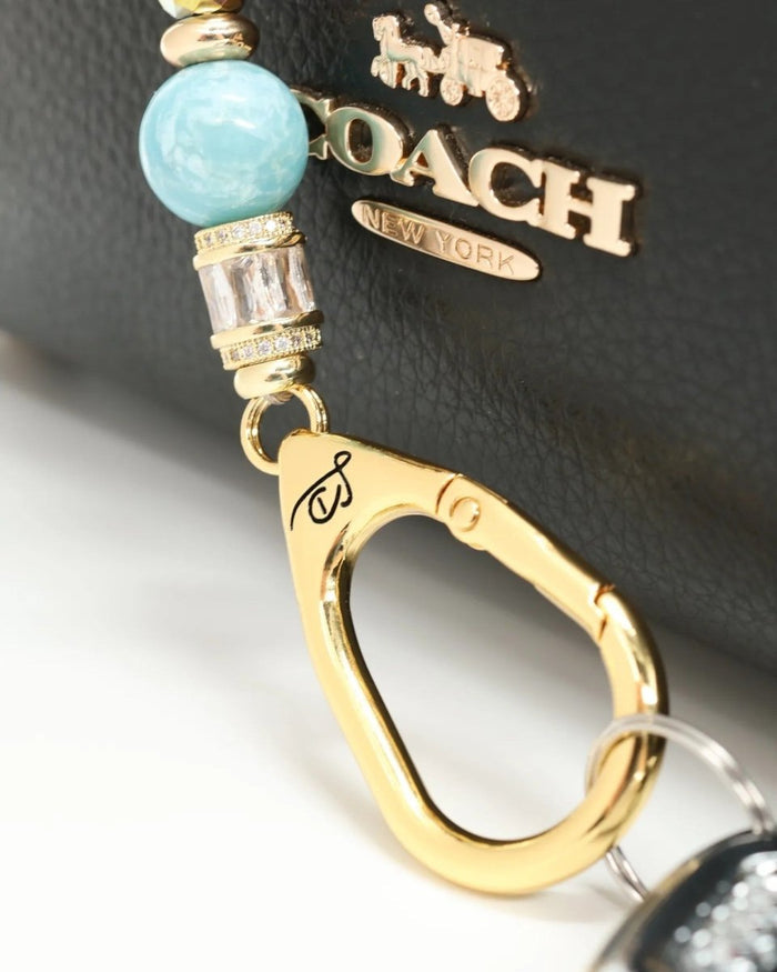 LD Keyfinder Petite Gilded Fantasy keychain with sky blue glass bead, gold accents, and blue flower charm.