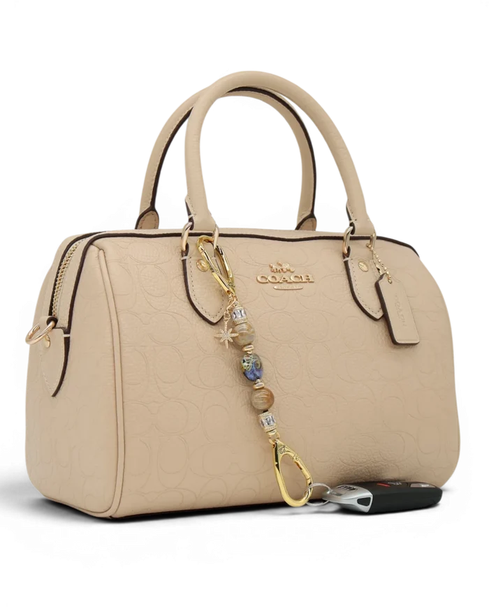 LD Keyfinder Petite Golden Nebula charm with purple, gold, and fossil coral beads, gold star charm, and gold hardware.