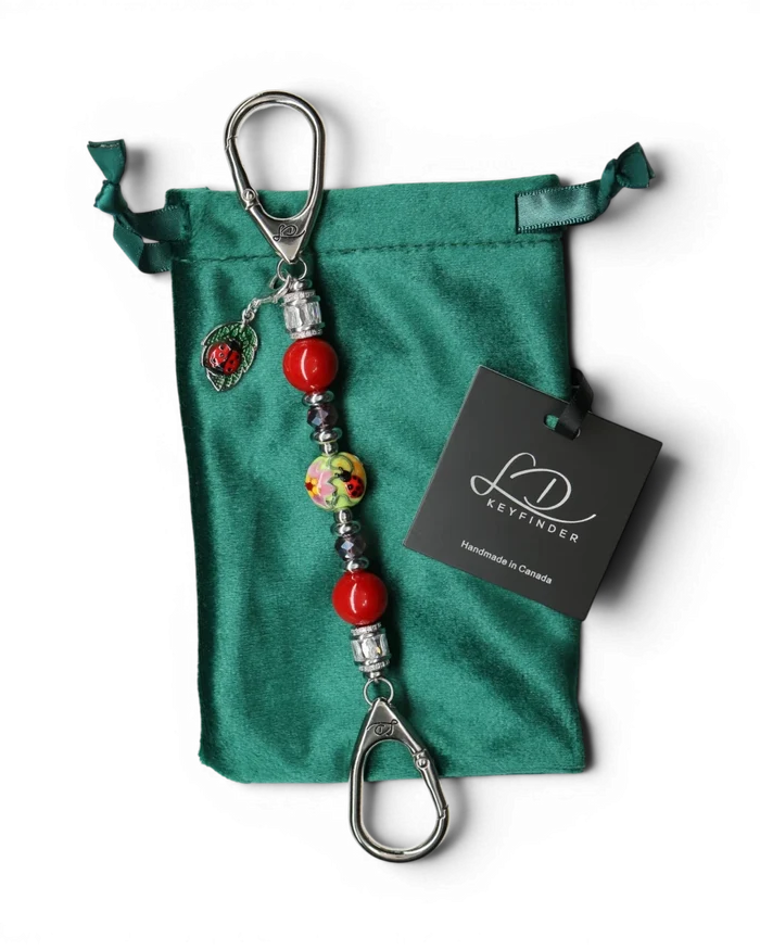 LD Keyfinder Petite Ladybug Love beaded accessory with artisan glass bead, red pearls, and ladybug charm on velvet bag