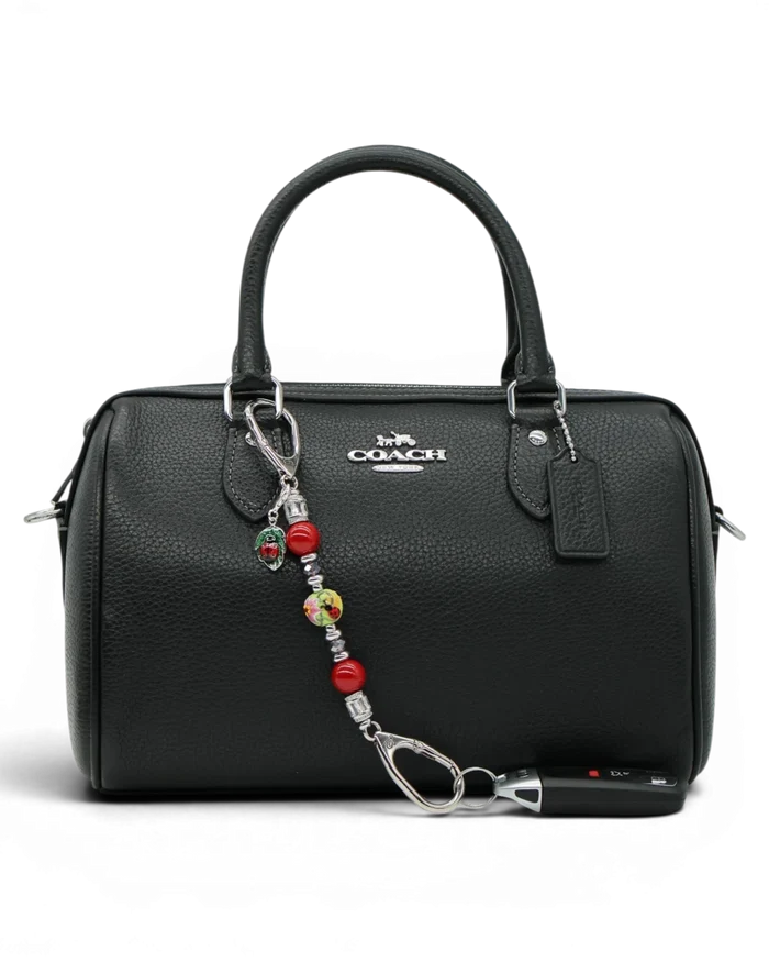 LD Keyfinder Petite Ladybug Love accessory with red shell pearls and artisan glass bead attached to a black handbag.
