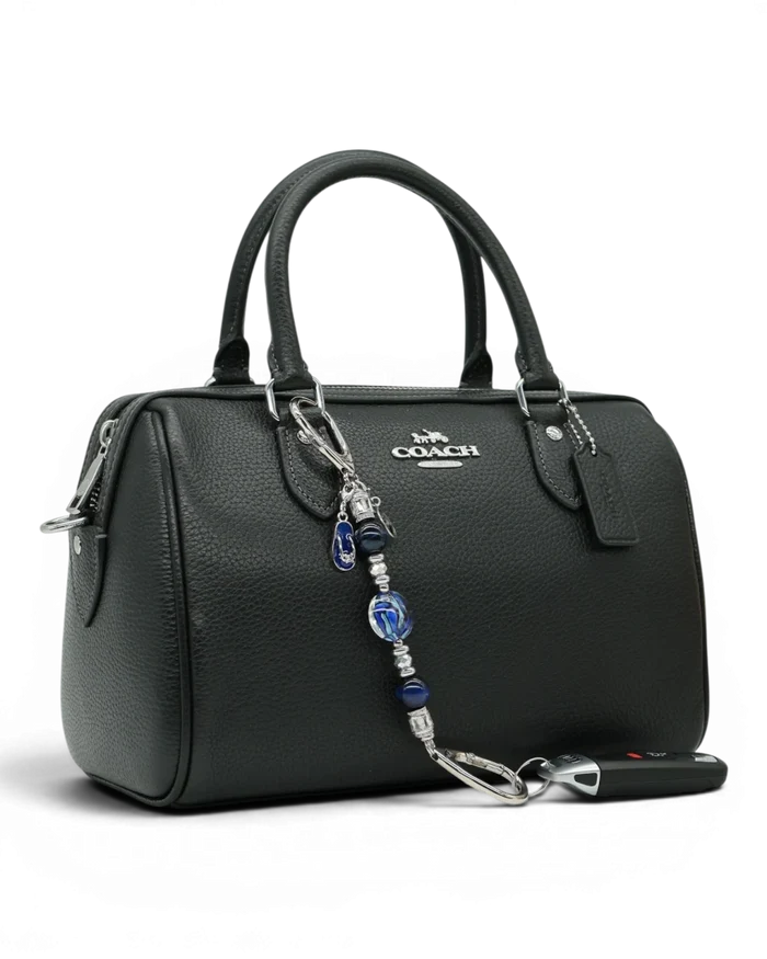 LD Keyfinder Ocean Mosaic Petite attached to a black leather handbag, featuring blue artisan glass and tiger eye beads.