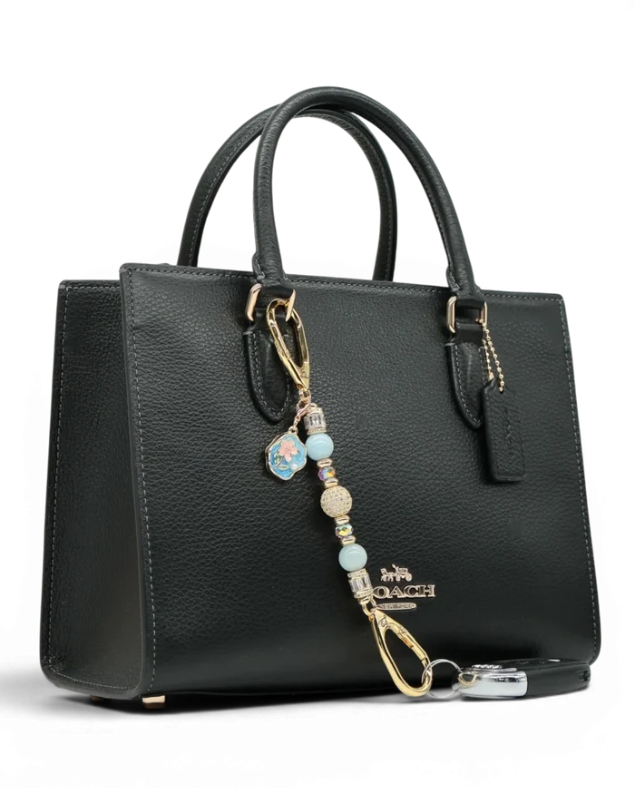 LD Keyfinder Petite Pastel Garden charm with aquamarine, pink glass beads, and gold-plated flower charm on a black handbag.