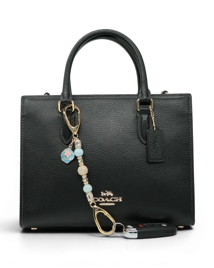 LD Keyfinder Petite Pastel Garden charm with aquamarine, pink glass beads, and gold-plated details on a black handbag.