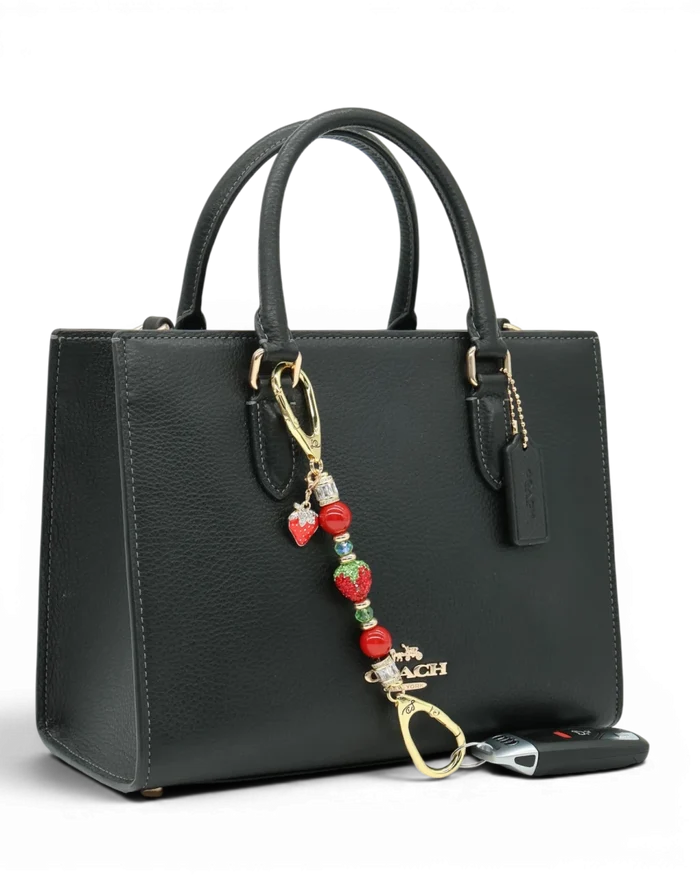 LD Keyfinder Petite Strawberry Fields charm with red pearls, green glass beads, and a crystal strawberry on a handbag.