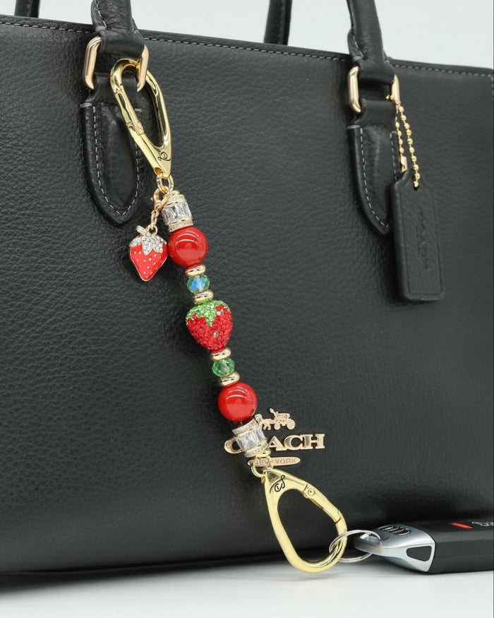 LD Keyfinder Petite Strawberry Fields charm with red pearls, green glass beads, and a crystal strawberry on a handbag.