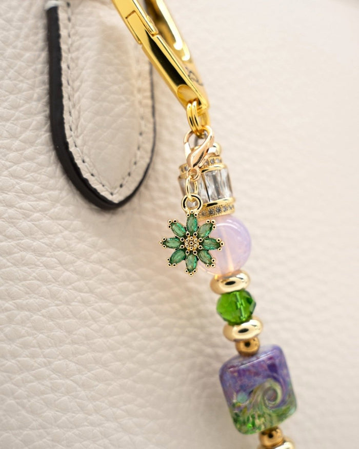 LD Keyfinder Petite Verdant Bloom accessory with lampwork glass, pink opalite, and gold flower charm on a handbag.