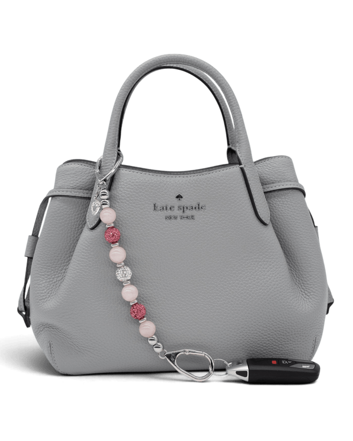 LD Keyfinder Princess Pink rose quartz beaded keychain with rhinestone heart charm attached to a grey leather handbag