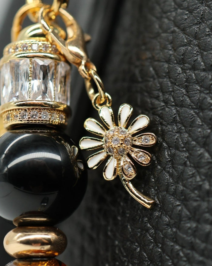 LD Keyfinder Queen Bee II charm bracelet with black obsidian, amber glass, gold accents, and a daisy charm.